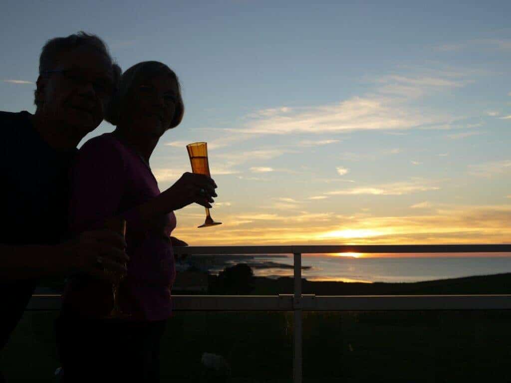 Couple d'amoureux sur une terrasse privative, dégustant une coupe de champagne face au coucher de soleil